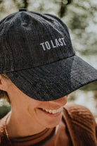Close-up of the grey Lobo cap highlighting the front embroidery detail with the phrase "To Last".