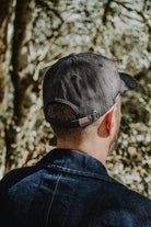 Rear view of the Lobo grey denim cap, showing the adjustable strap and side brand logo tag.
