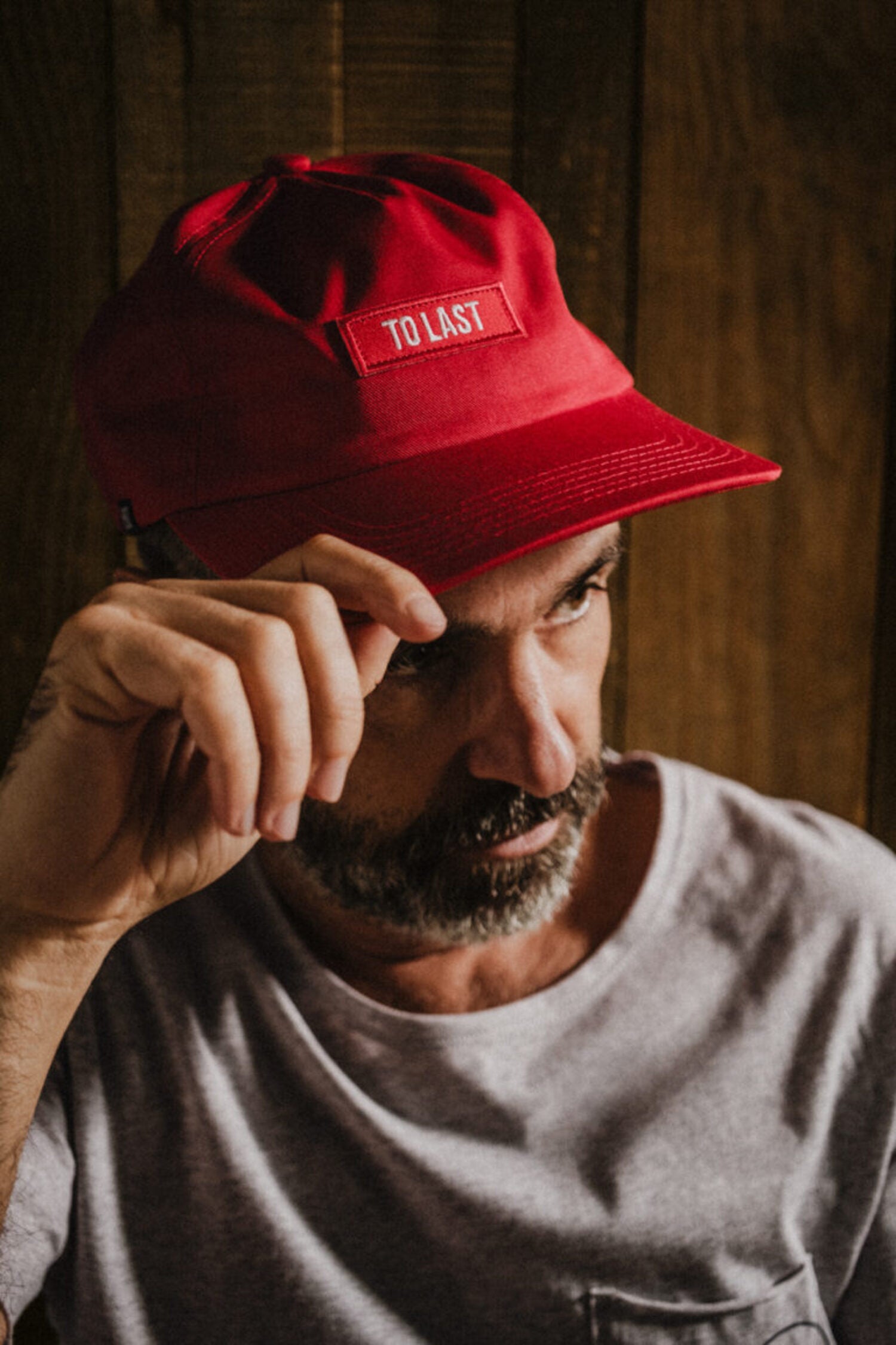 Bearded man wearing the LOBO Apparel "To Last" red cap, demonstrating the comfortable fit and urban casual style.
