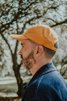 Side profile view of a man wearing the yellow Lobo cap, showing the brim structure and fit in an outdoor setting.