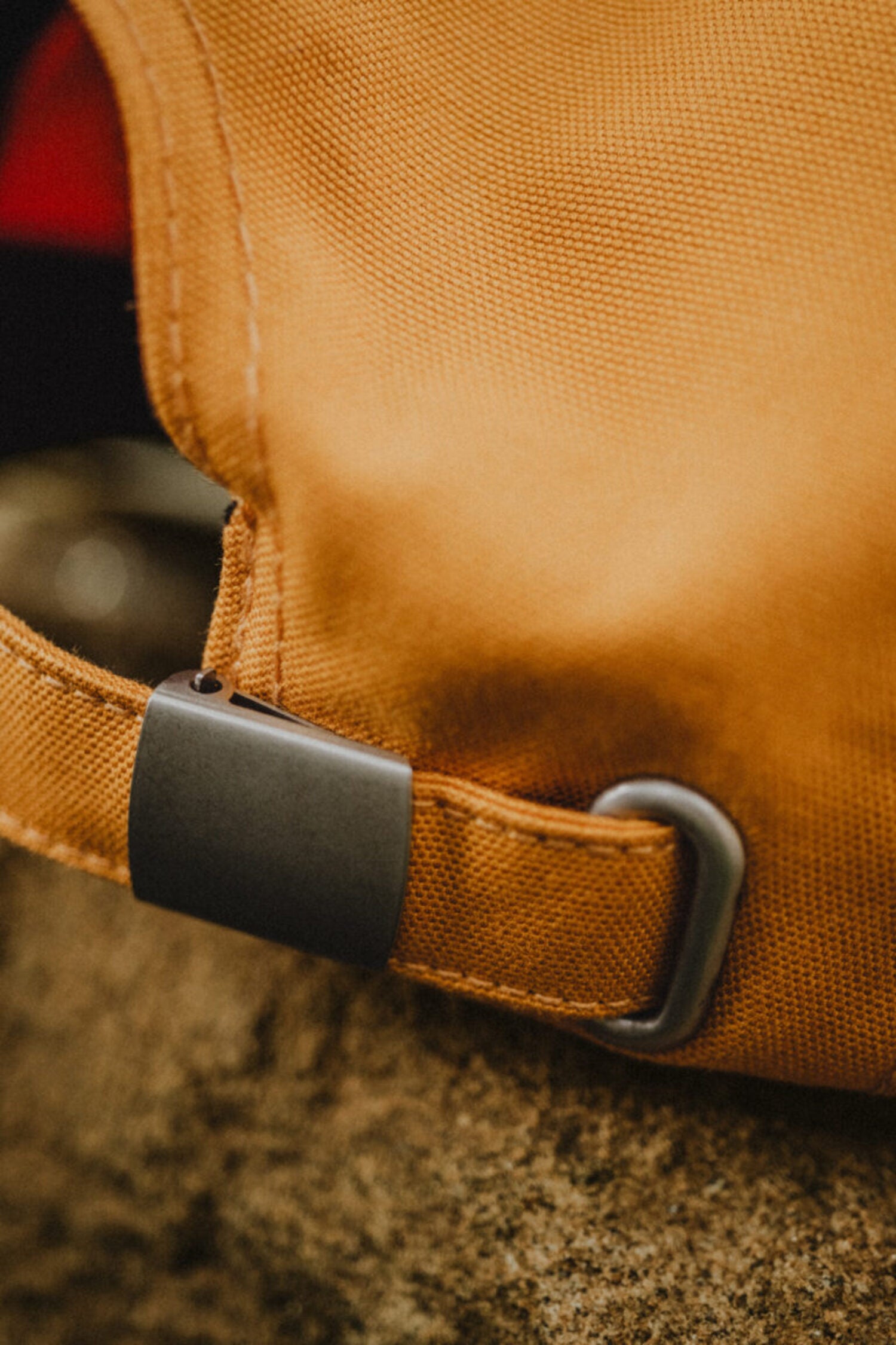 Close-up of the grey metal adjustable strap and fabric closure of the yellow Lobo cap, highlighting material quality.