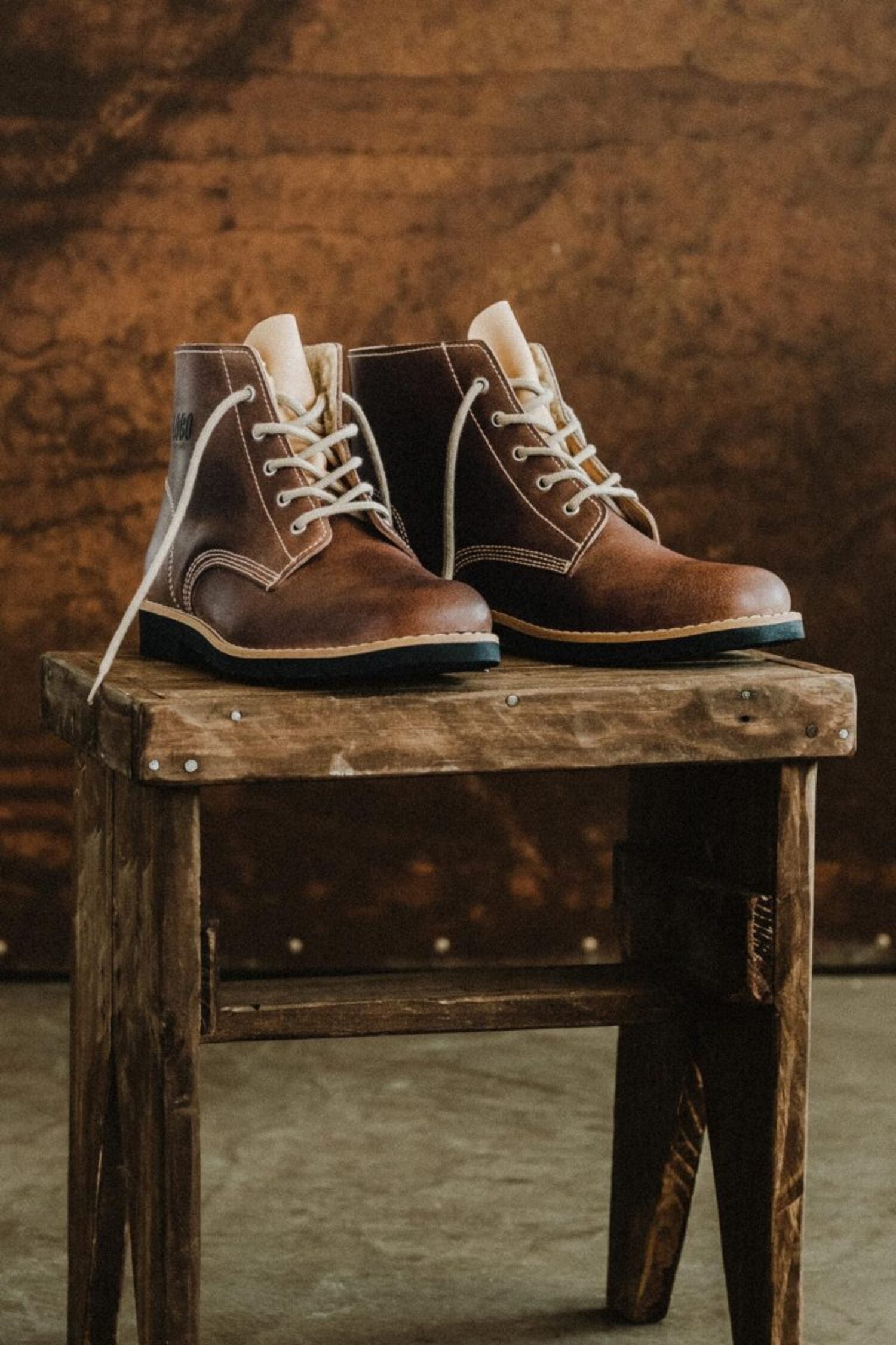 Lobo Warm Boots in premium leather with cream lace option on a rustic stand.