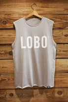 Unisex Lobo grey tank t-shirt made of high-quality cotton, featuring a white screen-printed logo and raw-edge finish, hanging on a wooden wall.