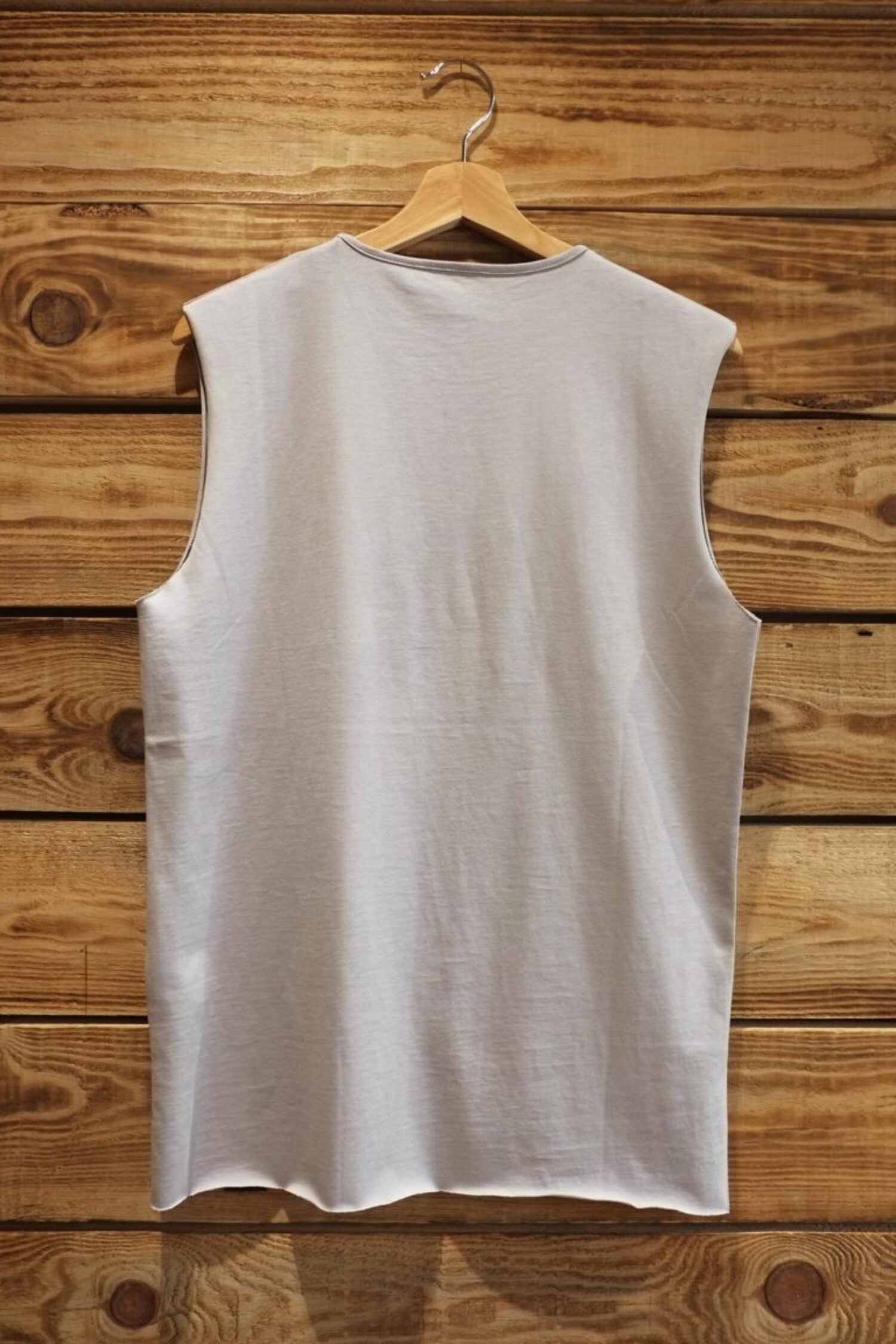 "Back view of the unisex Lobo grey tank t-shirt, highlighting the minimalist cut, premium cotton, and raw-edge hem finish.