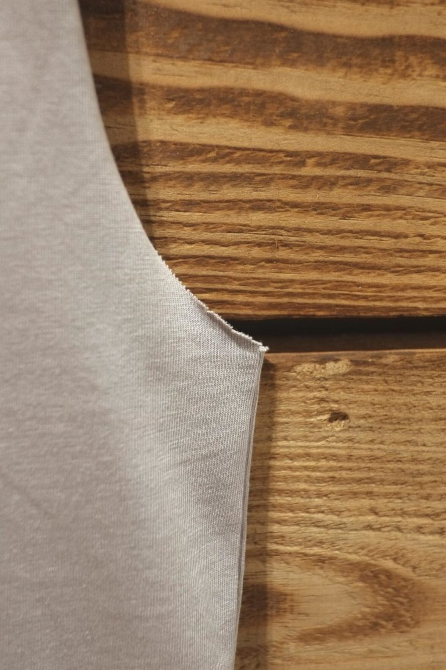 Close-up of the Lobo grey tank t-shirt armhole, showing the raw-edge finish and the high-quality cotton jersey fabric.