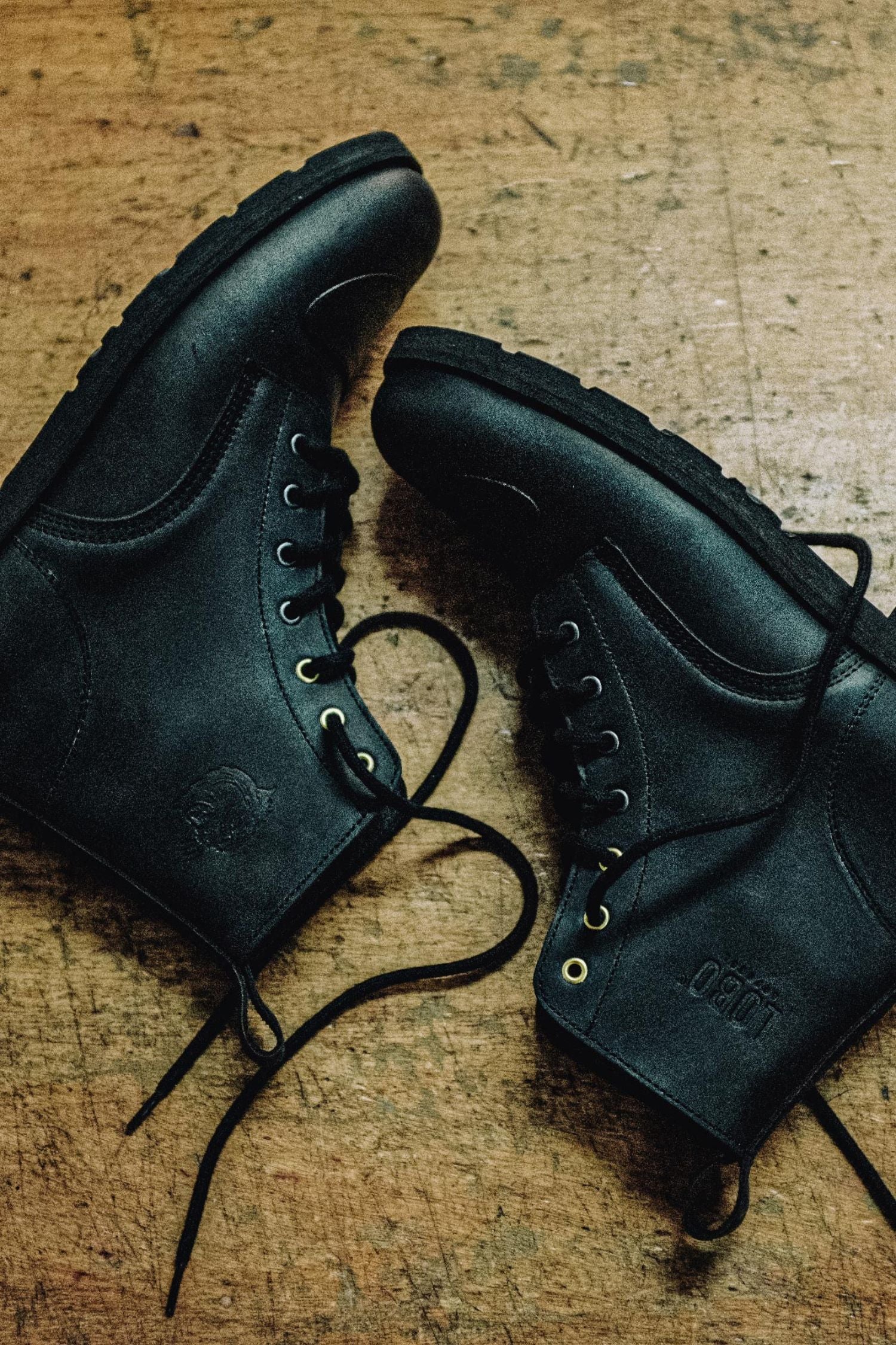 Black leather motorcycle boots by Lobo Apparel featuring toe reinforcement shifter protectors, black logos, and golden eyelets.