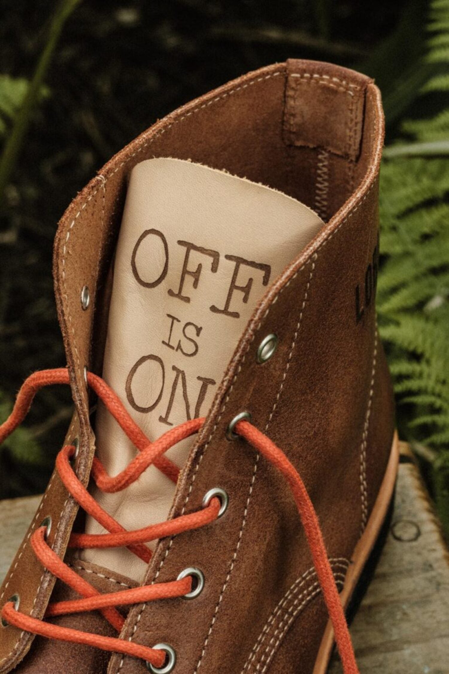 Close-up of the Lobo boot leather tongue with "OFF IS ON" embossed detail and orange cotton laces.