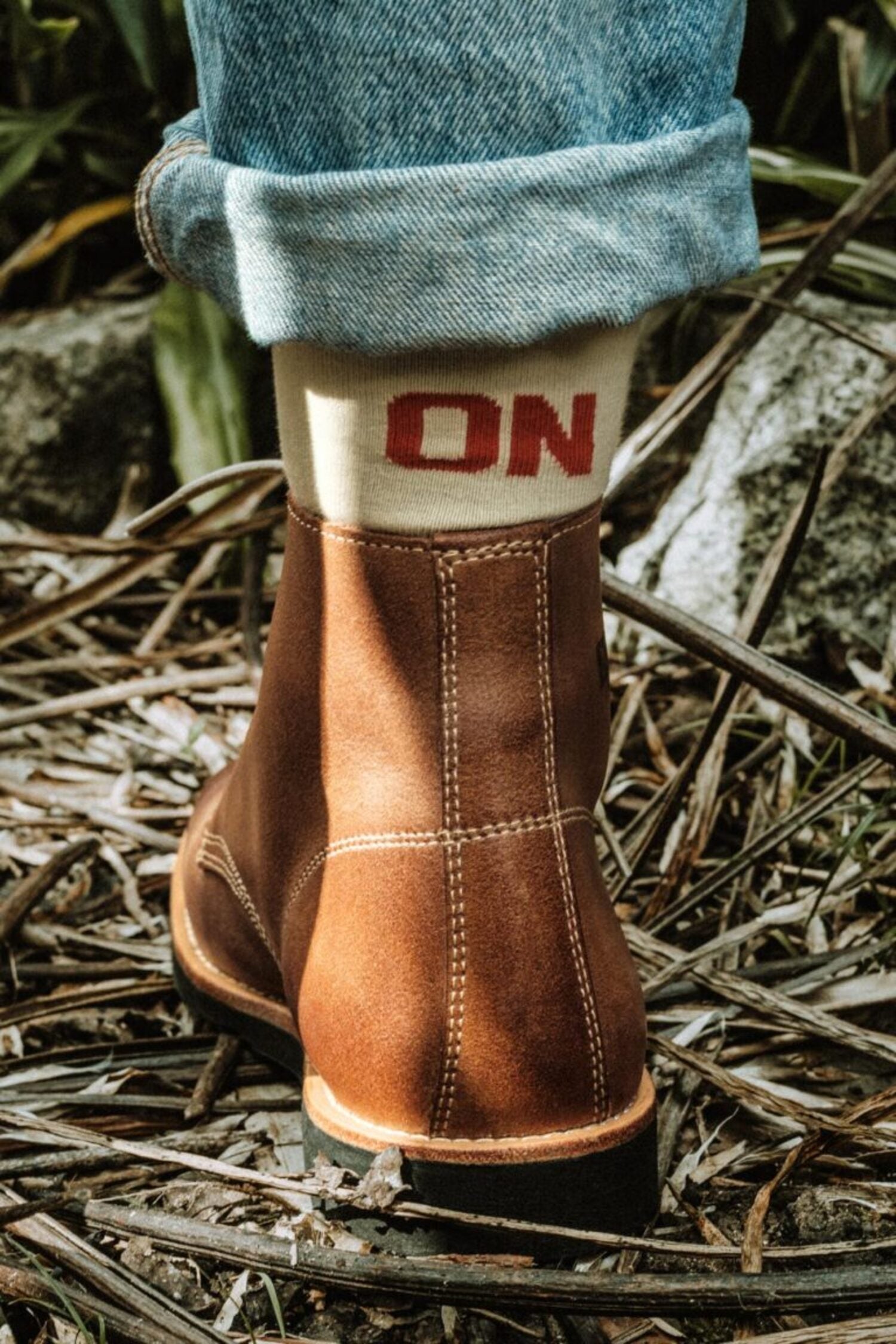 Detail of a handcrafted Lobo boot with a beige Naked Malt collection sock highlighting the word "ON" in red.