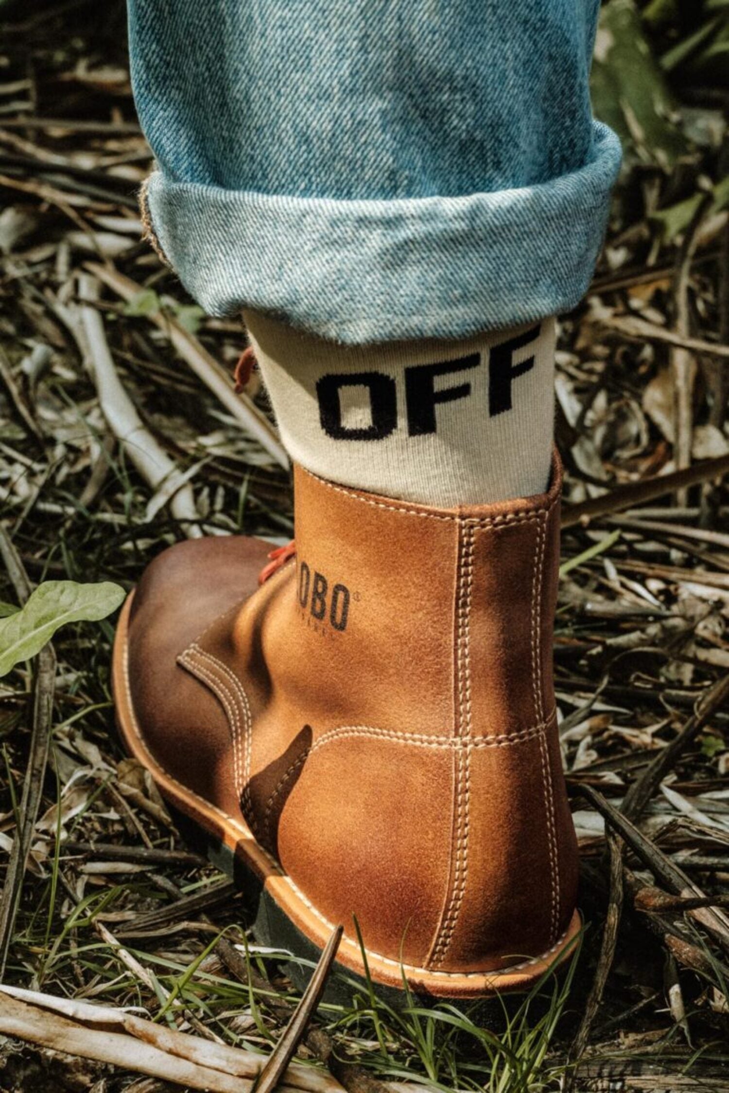 Close-up of a brown leather Lobo boot paired with a white collaboration sock featuring the word "OFF" in black lettering.