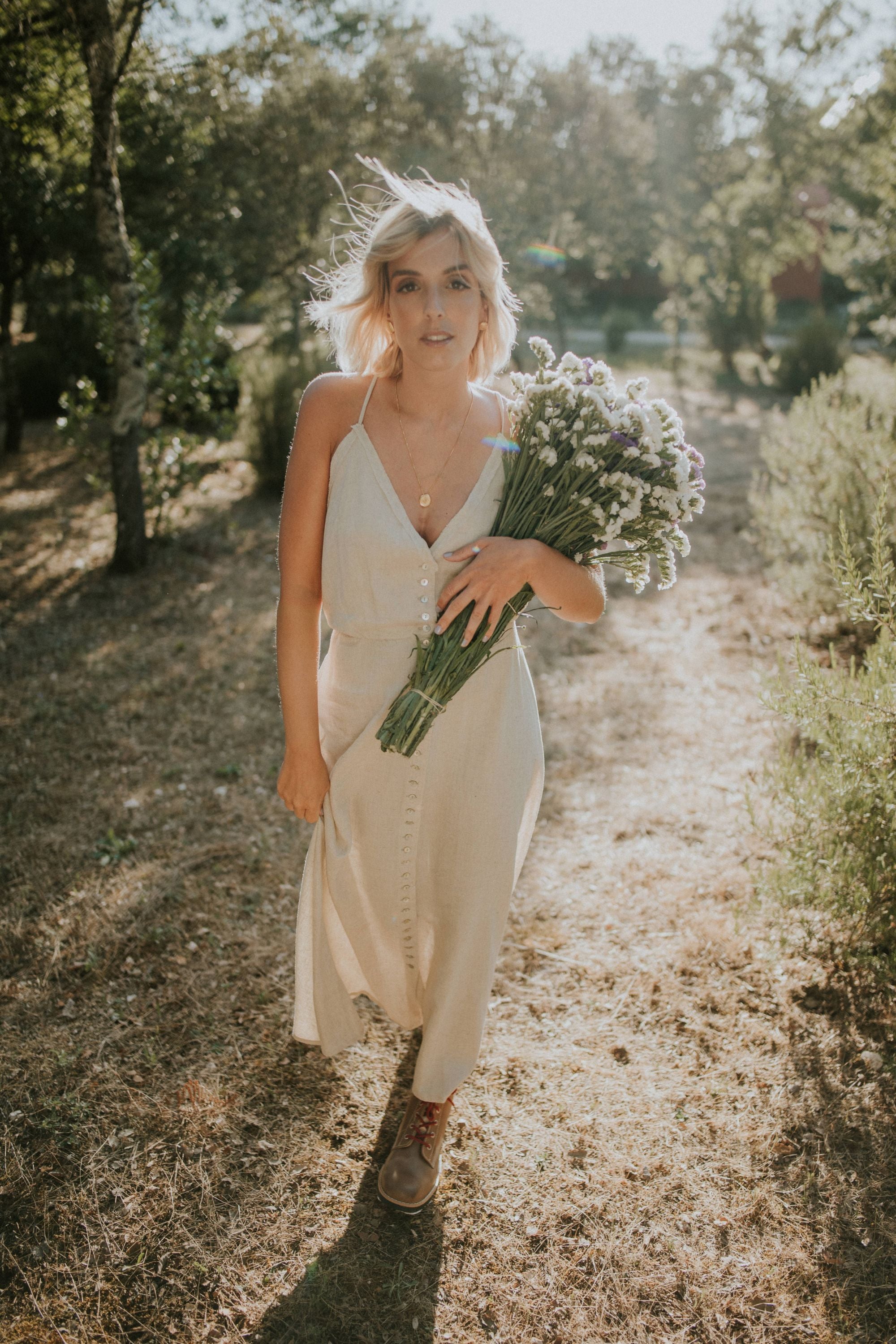 Blonde model walking in a field at sunset, holding flowers and wearing Lobo Raw Boots.