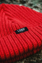 Close-up of the ribbed knit on the Manuel Red Beanie, highlighting the black "LOBO Apparel" label.