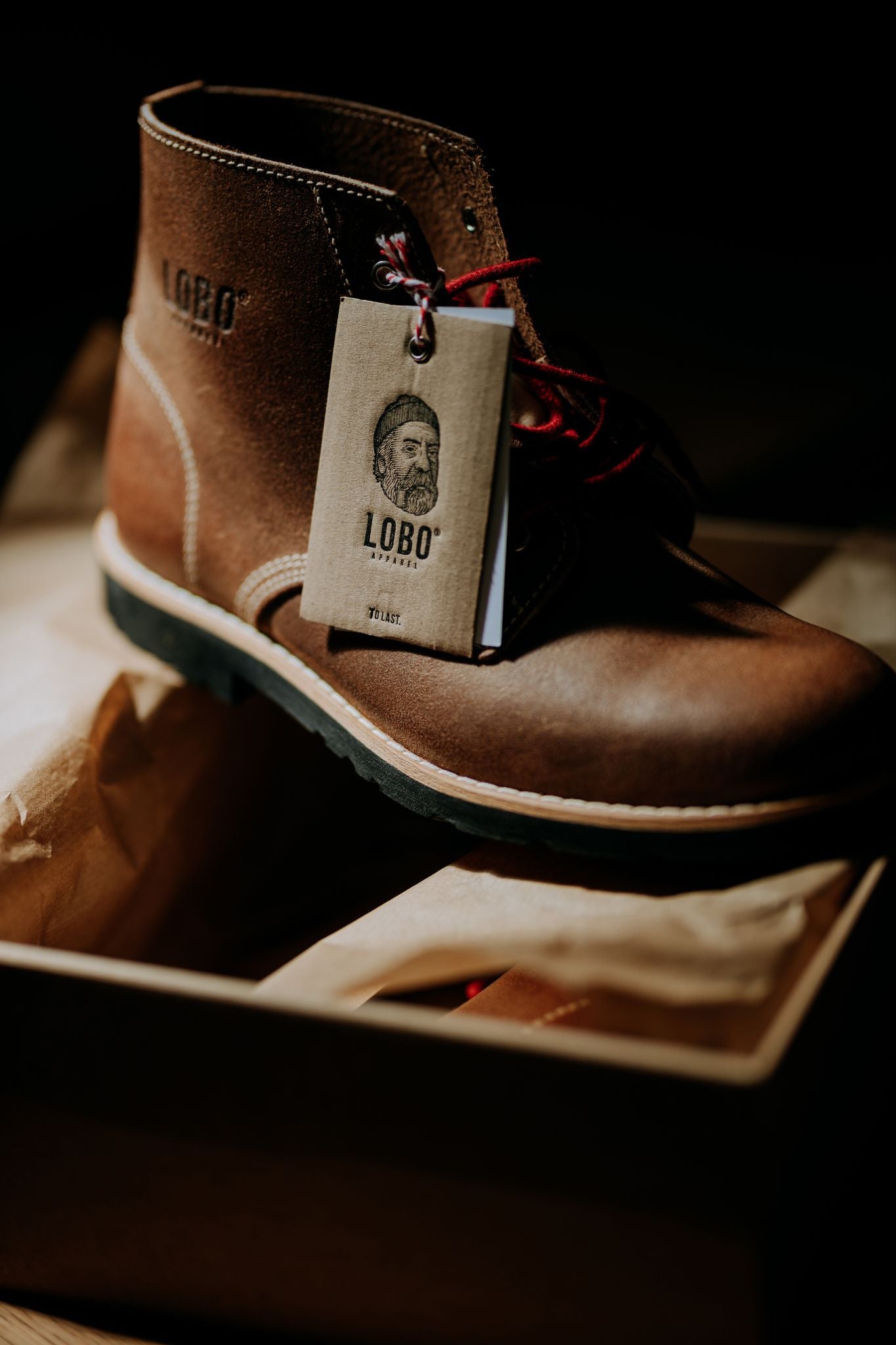 Close-up of the Lobo Raw Boots boot, focusing on the brand tag illustrated with a bearded man wearing a beanie and a pipe.