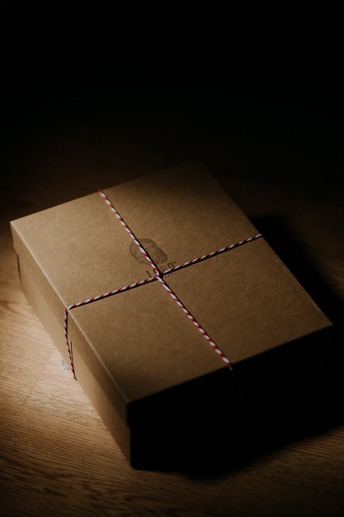 LOBO brand cardboard box closed and tied with a bicolor (red and white) string, featuring the logo of a bearded man with a beanie and a pipe.