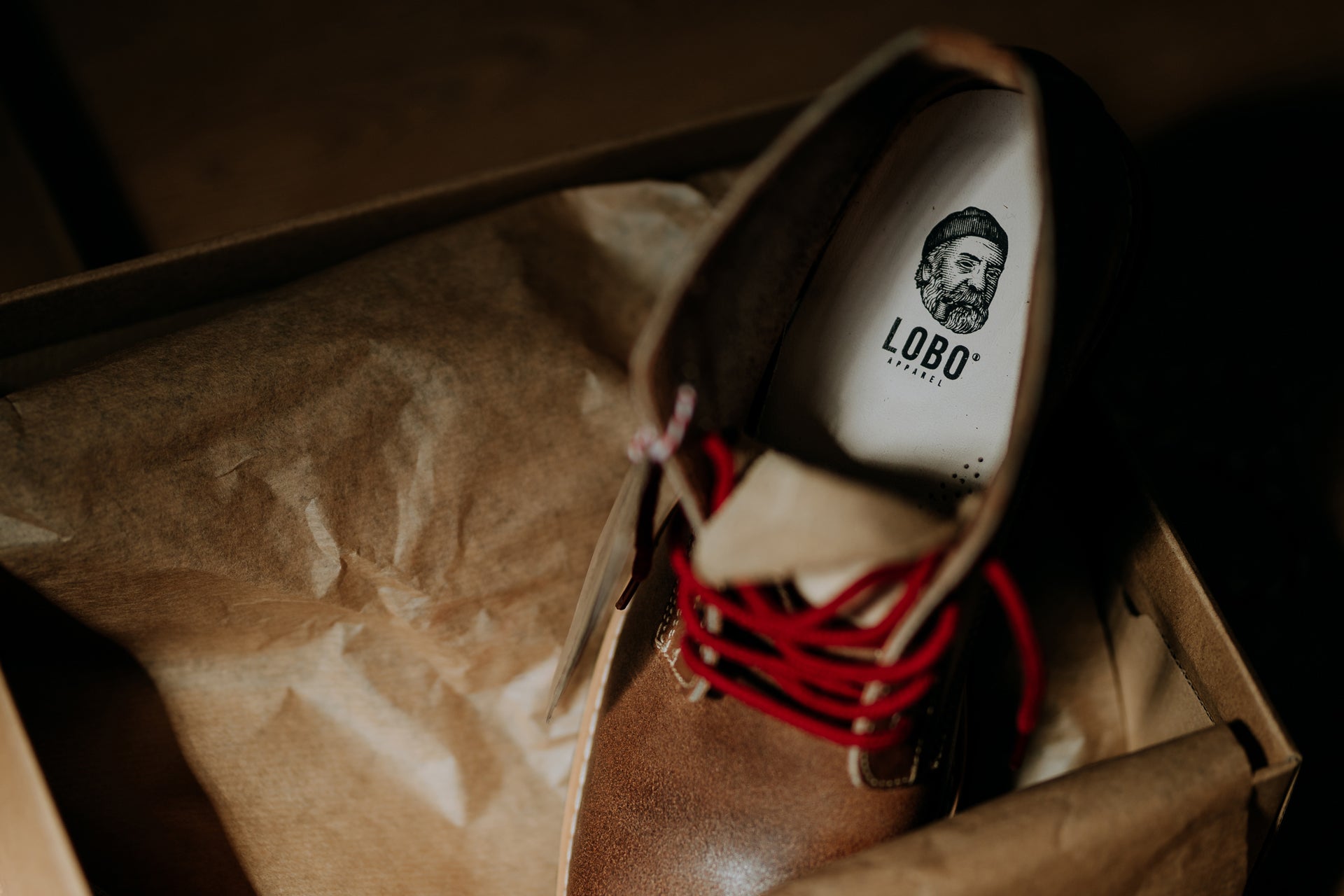 Top view of the interior of the Lobo Raw Boots, highlighting the white insole with the bearded man logo and the prominent red laces.