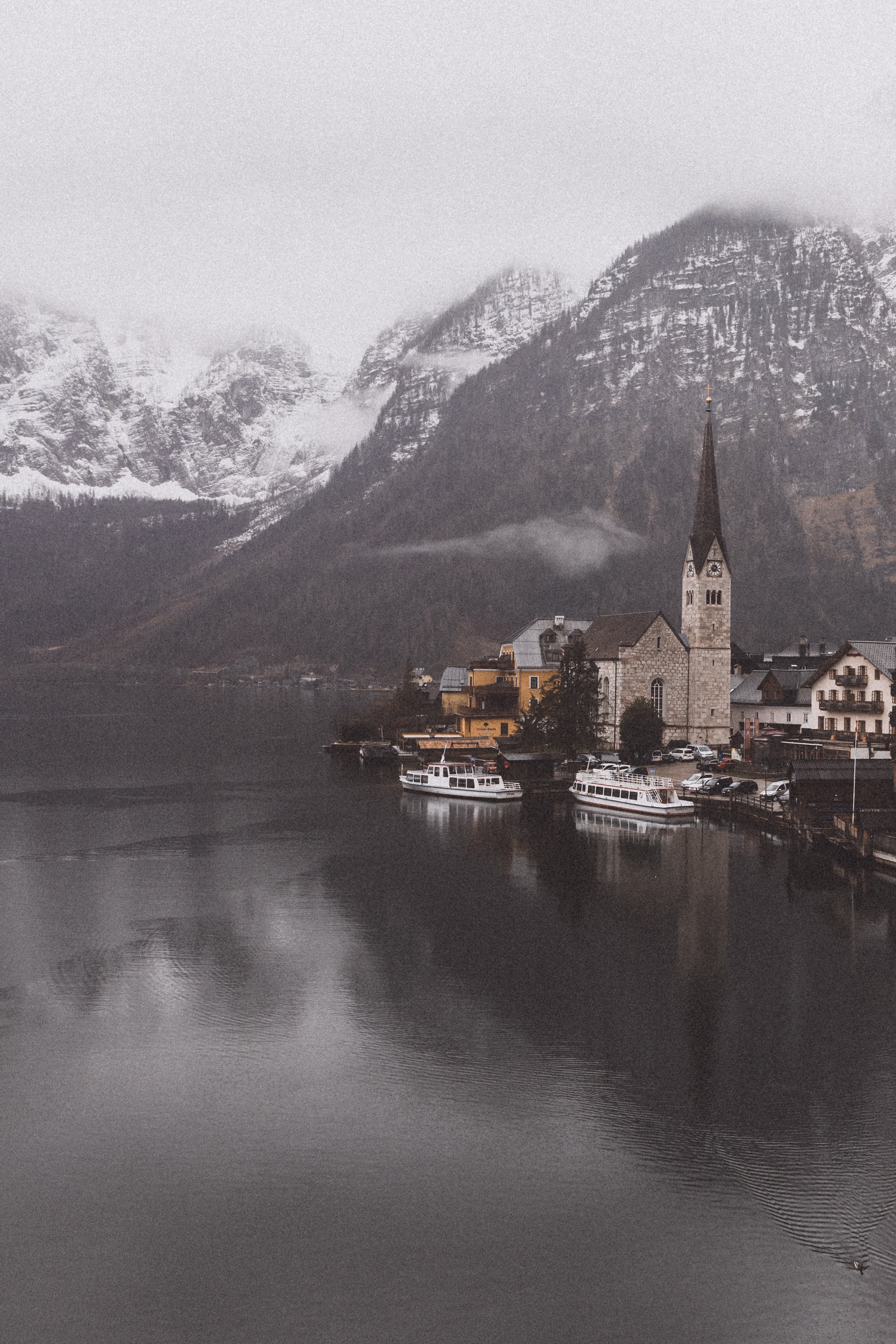 Panoramic view of the historic village of Hallstatt, Austria, featuring its iconic lakeside church and snow-capped mountains in the background.