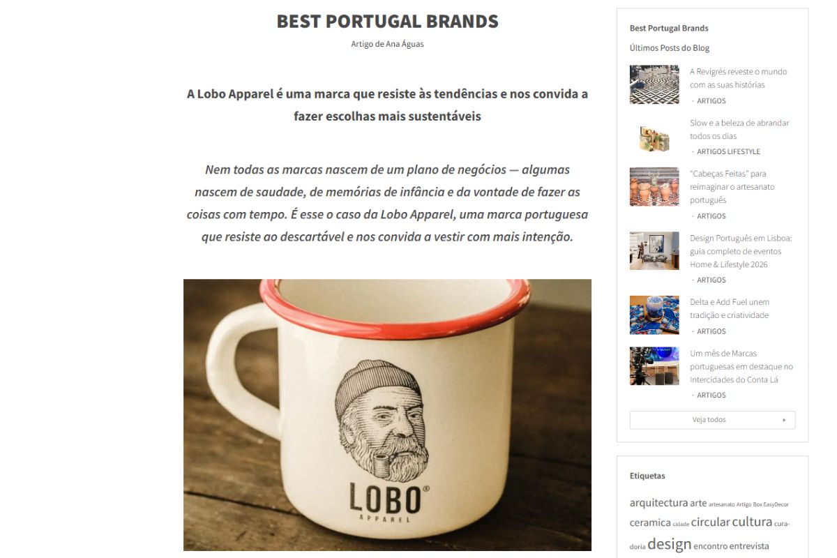 White enamel mug featuring the Lobo Apparel logo and a red rim, placed on a wooden table. Featured photo from the Best Portugal Brands article.