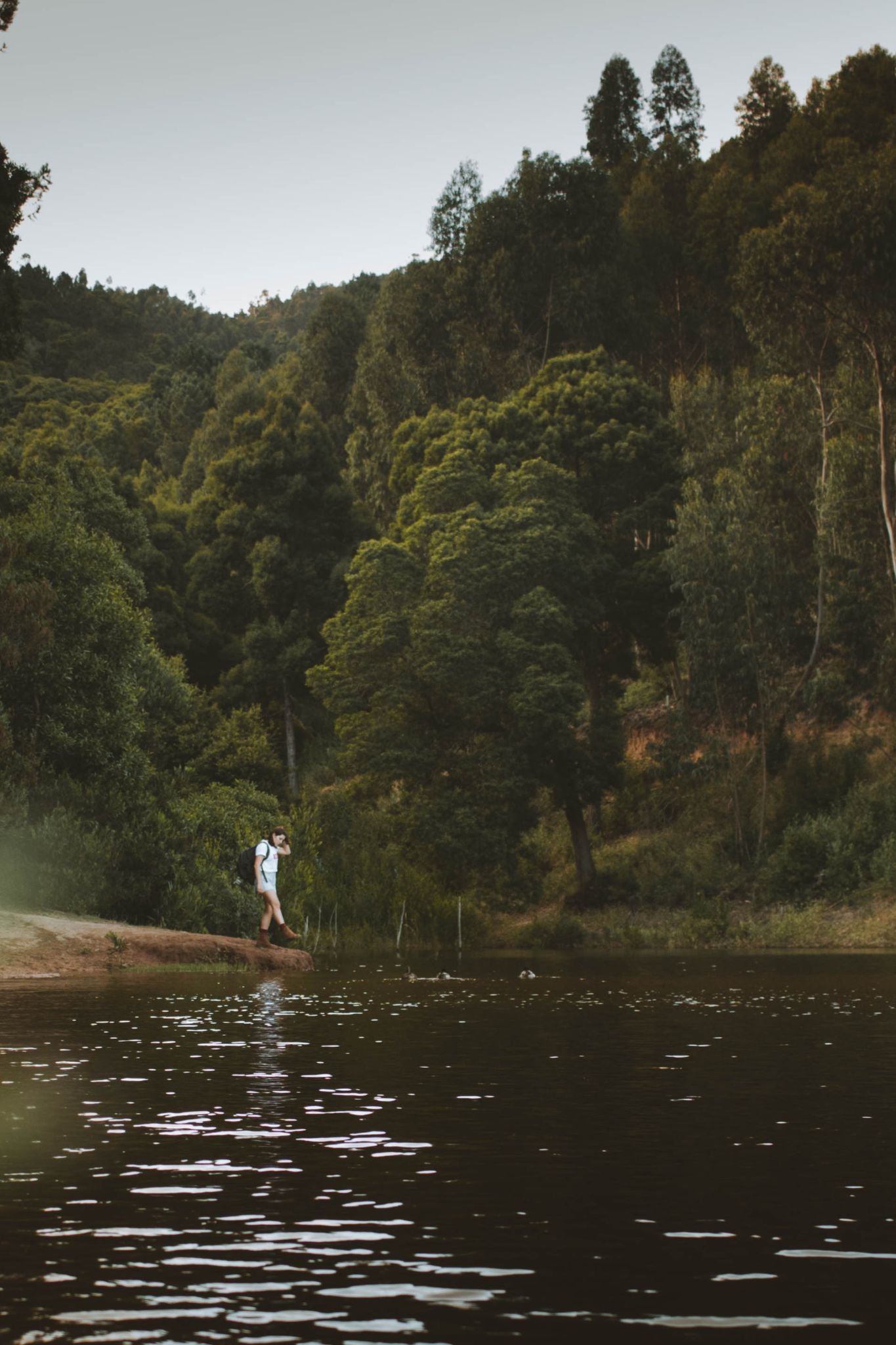 Woman walking by the Rio da Mula riverbank wearing the white To Last t-shirt.
