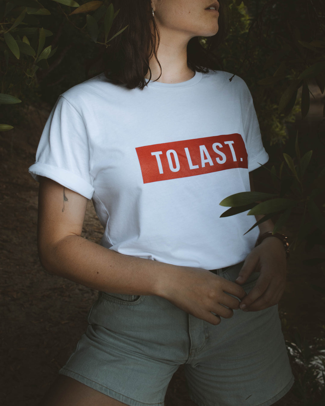Close-up shot of the white cotton To Last t-shirt, highlighting the fit and the "TO LAST." print.