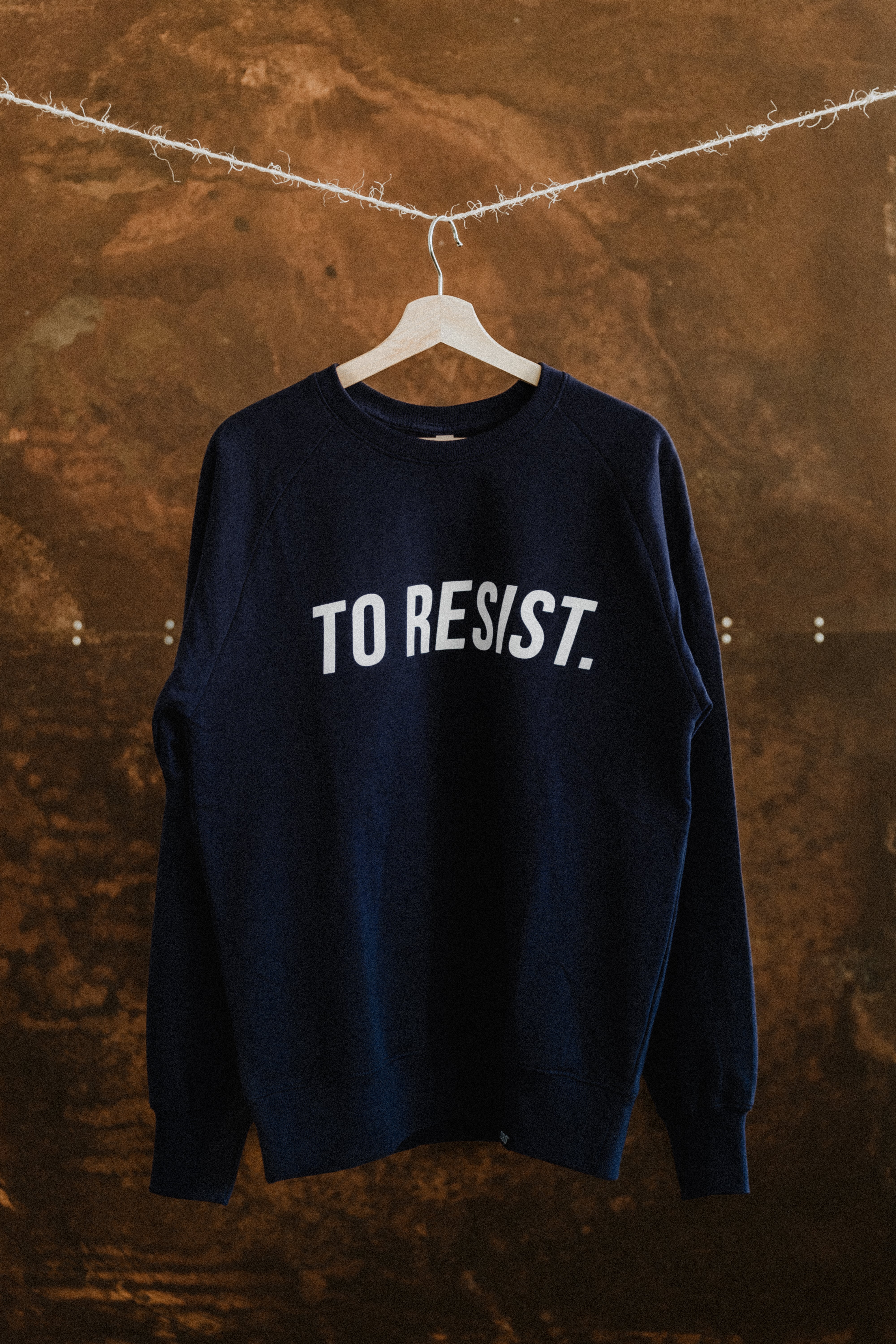 Dark blue unisex sweatshirt featuring the "TO RESIST" white print by Portuguese clothing brand Lobo Apparel, showcasing urban sustainable fashion.