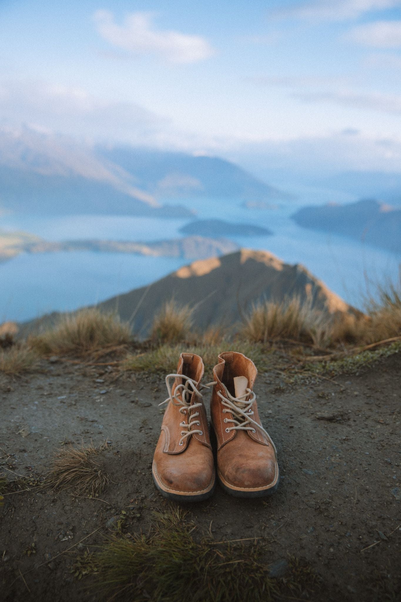 Close-up of brown leather LOBO Raw Boots on a mountain trail overlooking an alpine lake.