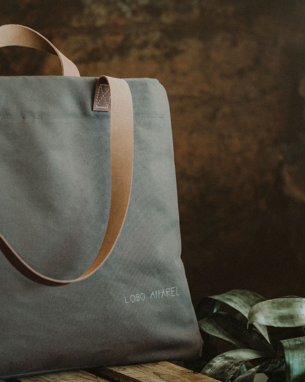 Close-up of the Lobo Apparel canvas bag highlighting the hand-embroidered brand name and natural leather strap.