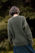 Back view of the Lobo Apparel unisex Verde Grisalho sweater, showcasing the textured knit pattern and comfortable fit in a natural outdoor setting.