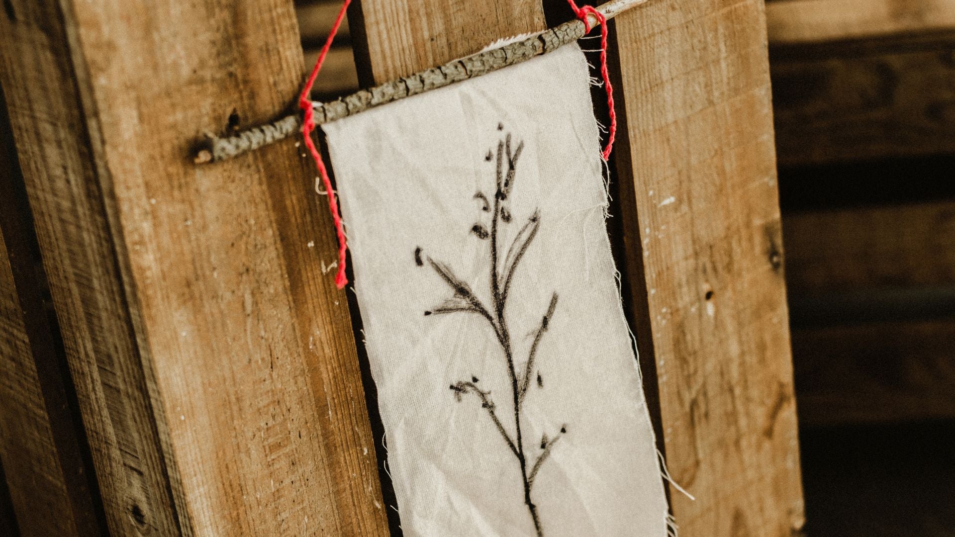 Rustic fabric decoration with botanical illustration hanging on a wooden structure by Lobo Apparel.
