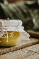 Close-up of the glass jar containing yellow beeswax and olive oil for deep leather conditioning and hydration.