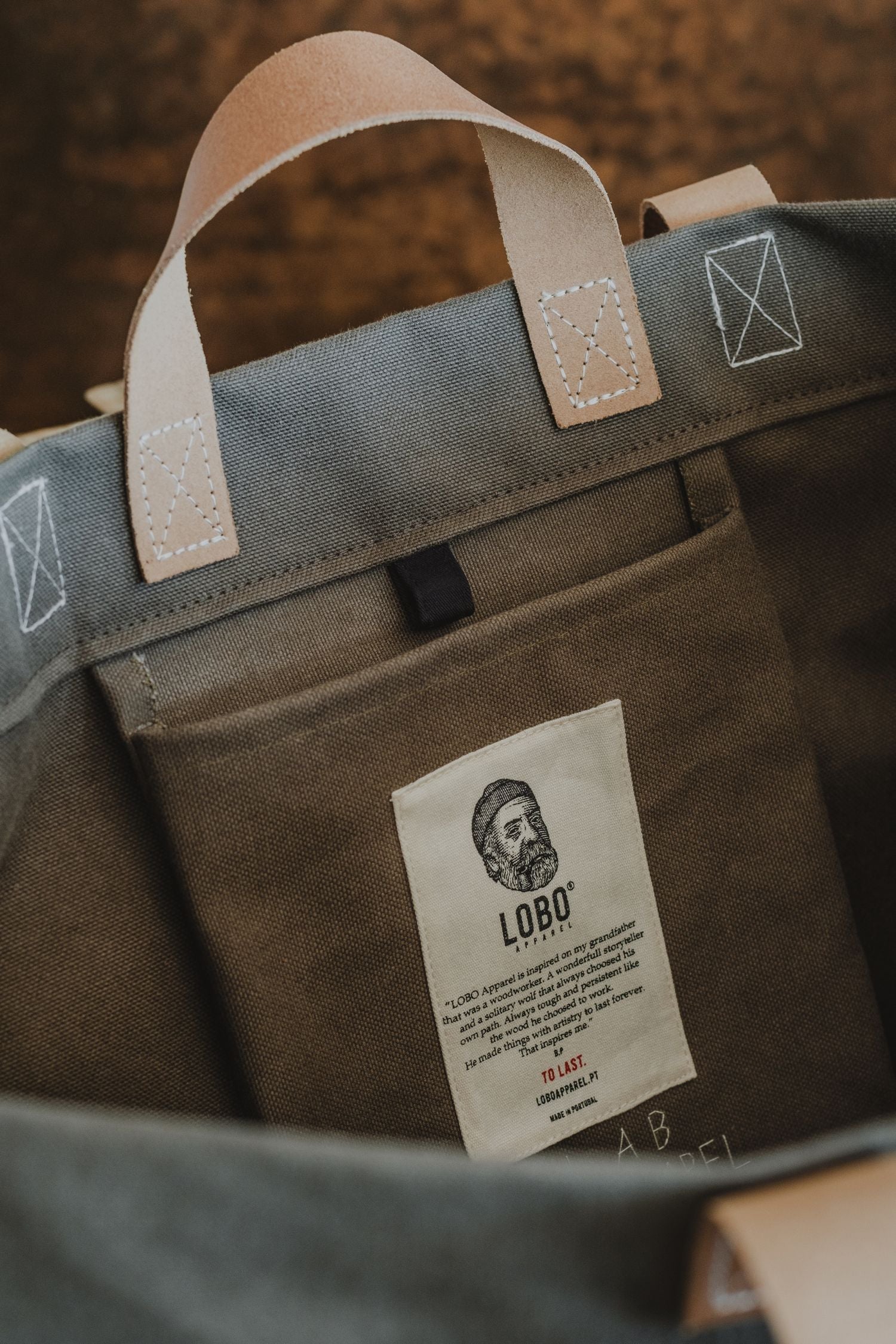 Close-up of canvas bag interior featuring the Lobo Apparel woven label with the logo of a bearded man wearing a beanie and smoking a pipe.